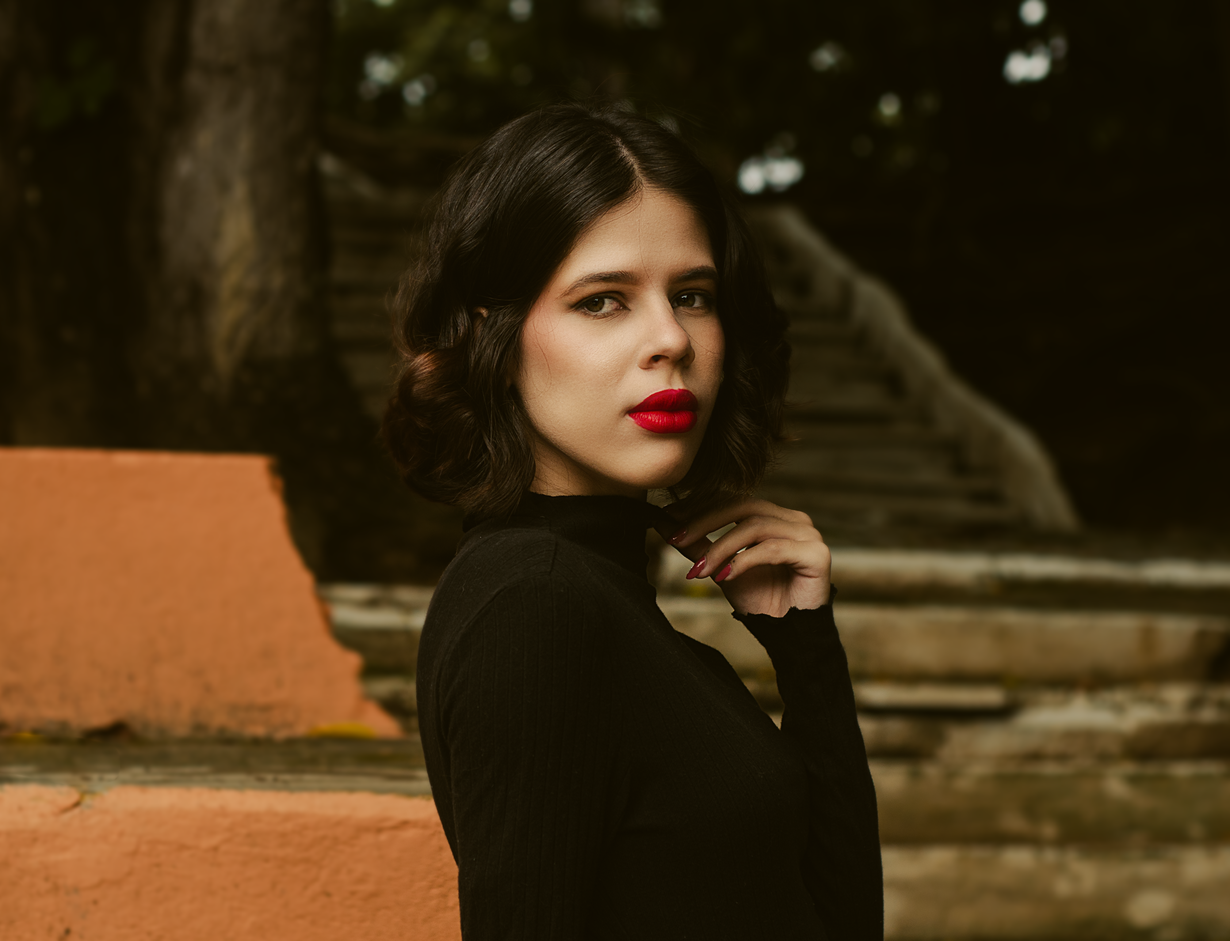 Stylish portrait of a woman with red lipstick against rustic outdoor stairs.