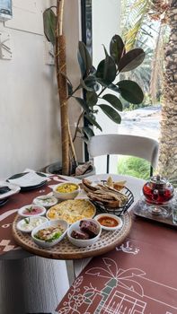 A scenic Middle Eastern brunch setup featuring mezze dishes, naan, and tea in an outdoor setting.