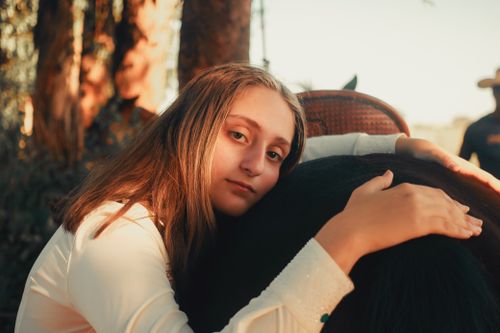 Free A young girl lovingly hugs her horse in a peaceful forest setting, highlighting friendship and nature. Stock Photo