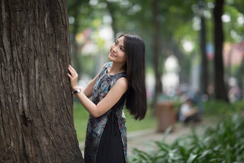 бесплатная Улыбающаяся женщина перед стволом дерева Стоковое фото