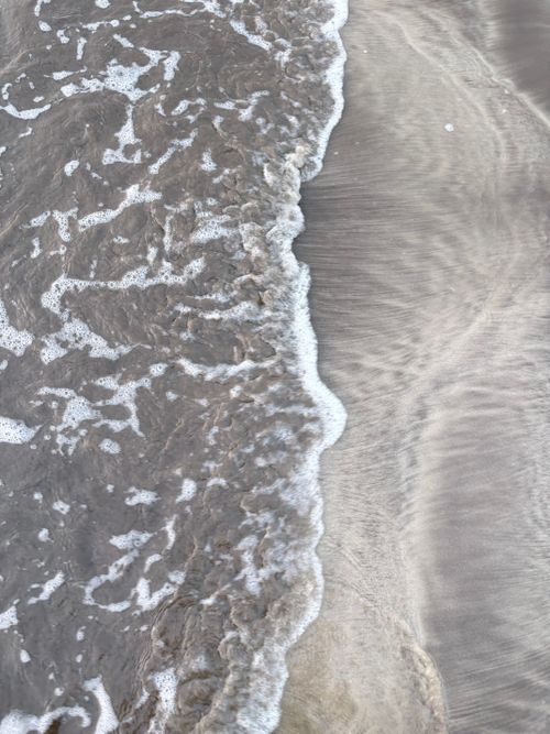 Free Close-up view of gentle ocean waves rolling onto a sandy beach, creating a serene and natural pattern. Stock Photo