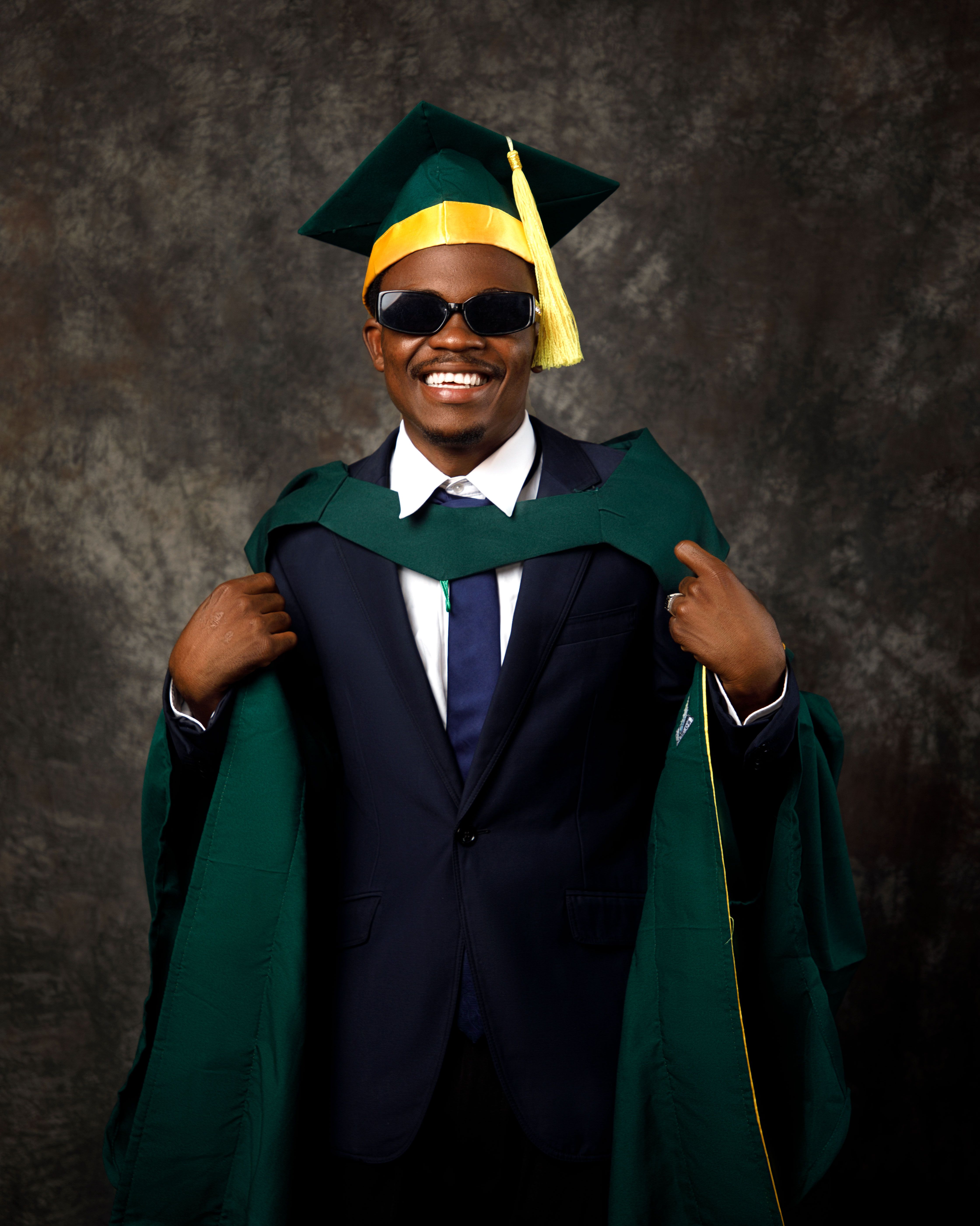 A man in a graduation gown sitting in a chair  Free Stock Photo