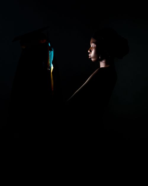 Free A striking low-key portrait of a graduate in profile, showcasing a graduation cap in dramatic lighting. Stock Photo