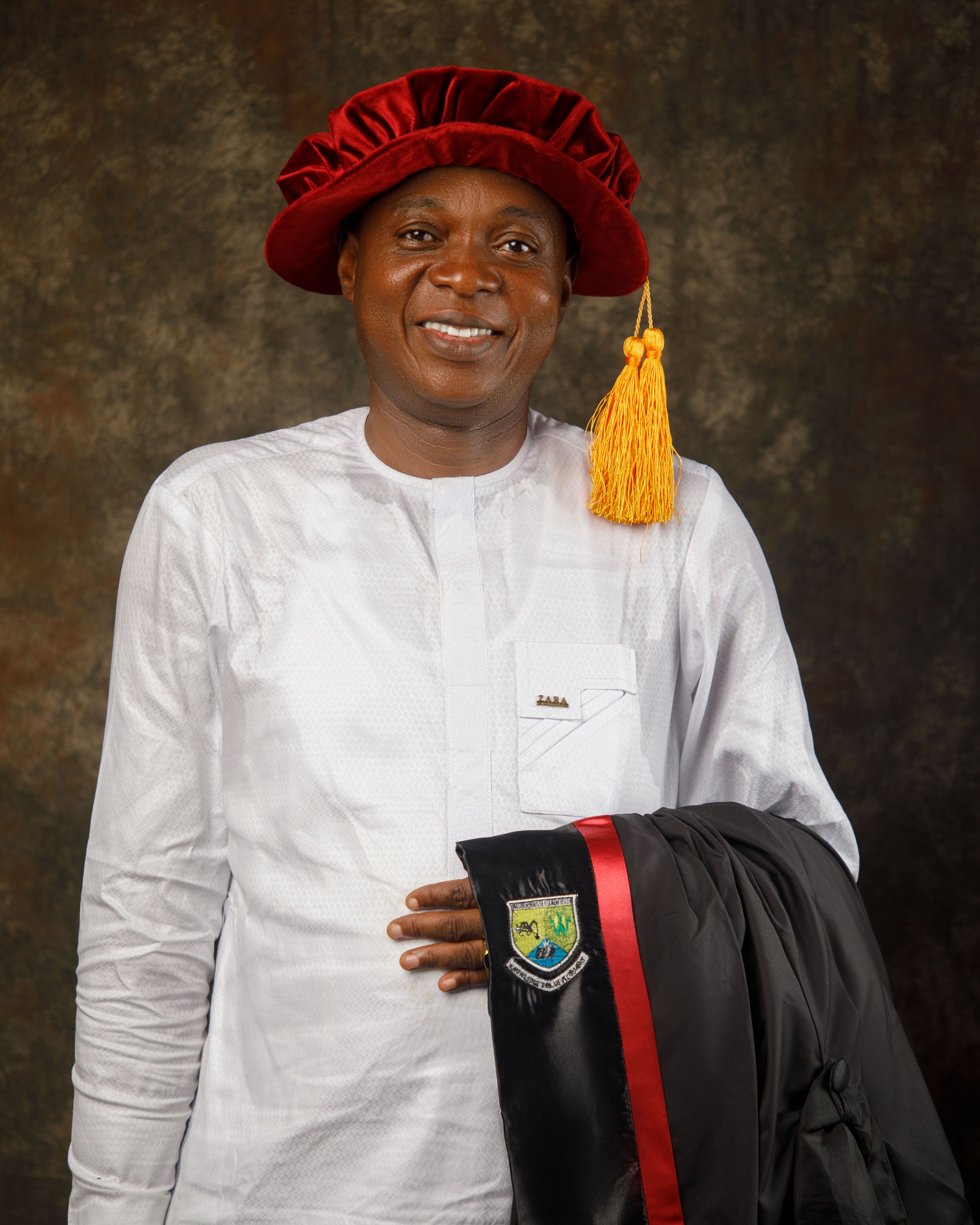 Proud graduate in ceremonial attire, smiling confidently at the camera.