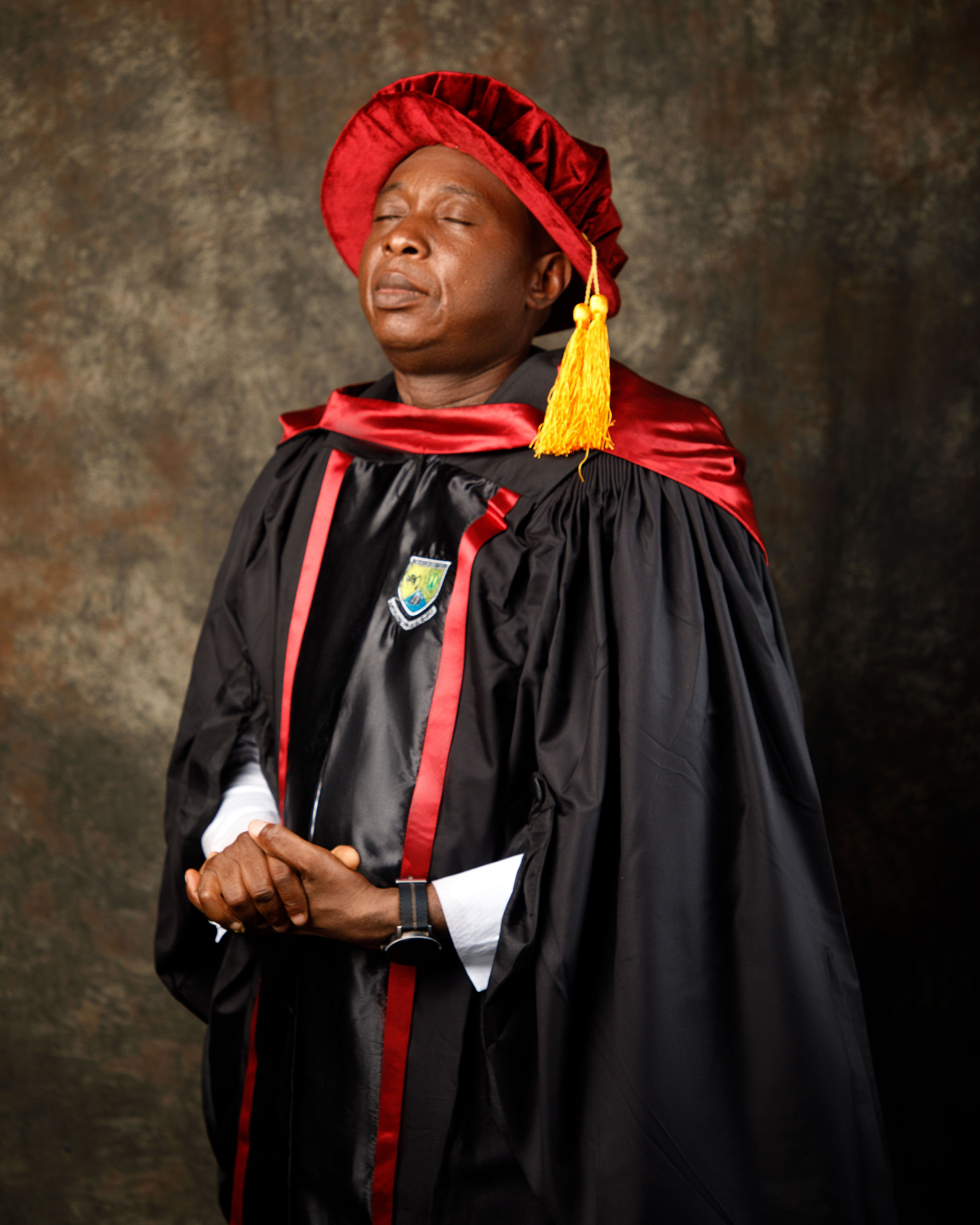 Adult male in graduation gown and cap, posing proudly.