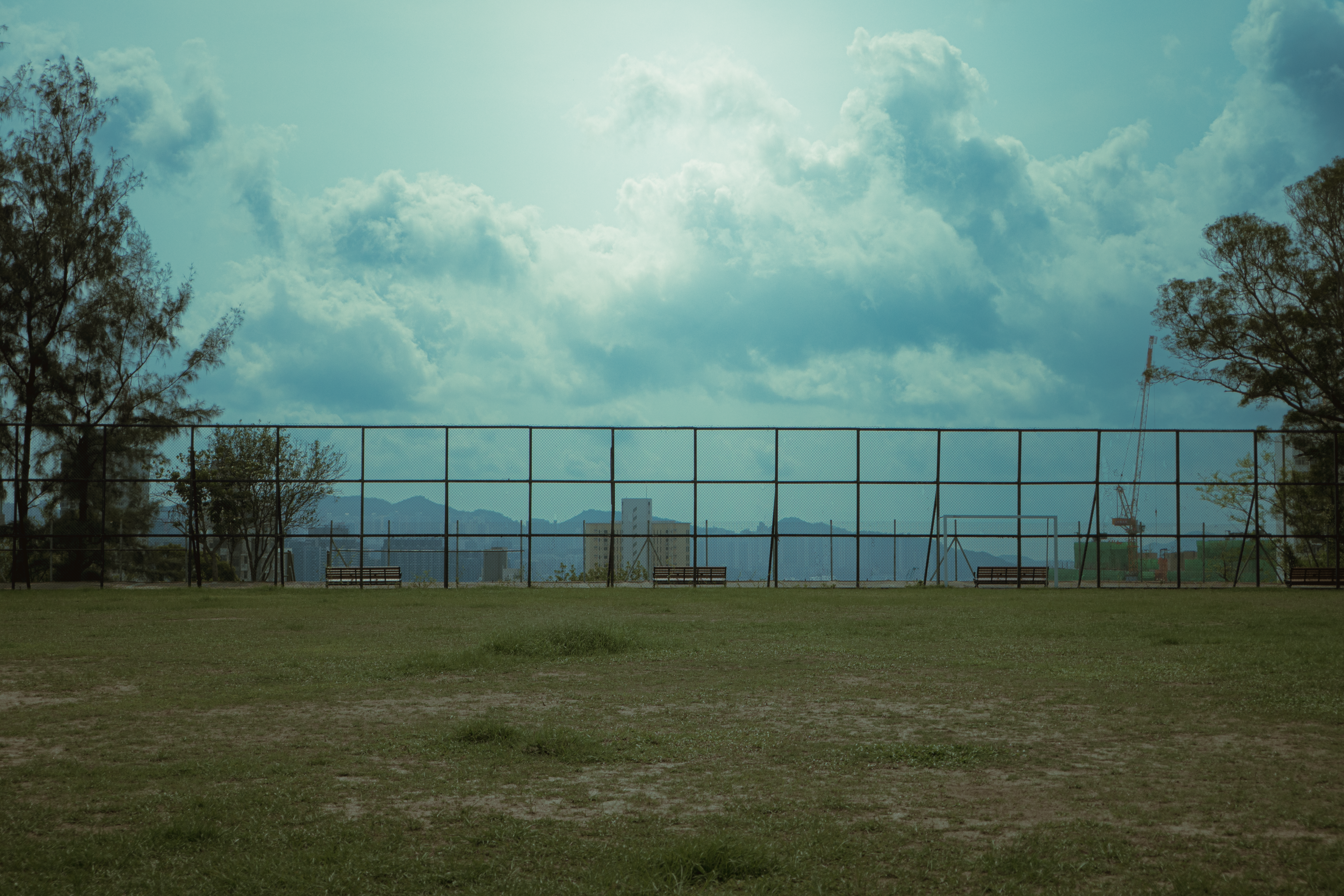 An empty bench in a city park under a cloudy afternoon sky
