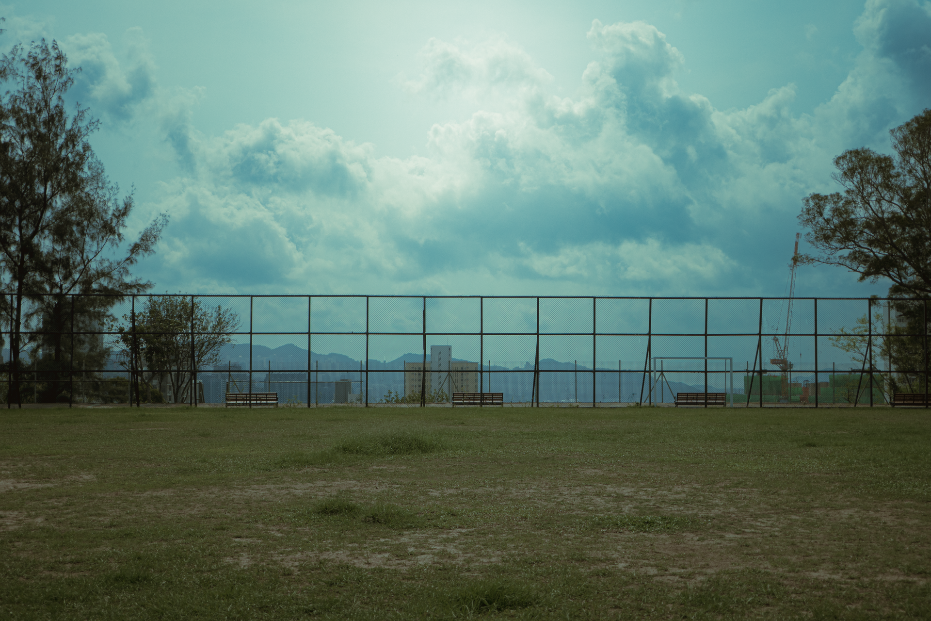 An empty bench in a city park under a cloudy afternoon sky