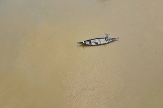 Drone footage of a single boat floating on a calm river in Bangladesh, showcasing serenity and simple lifestyle.