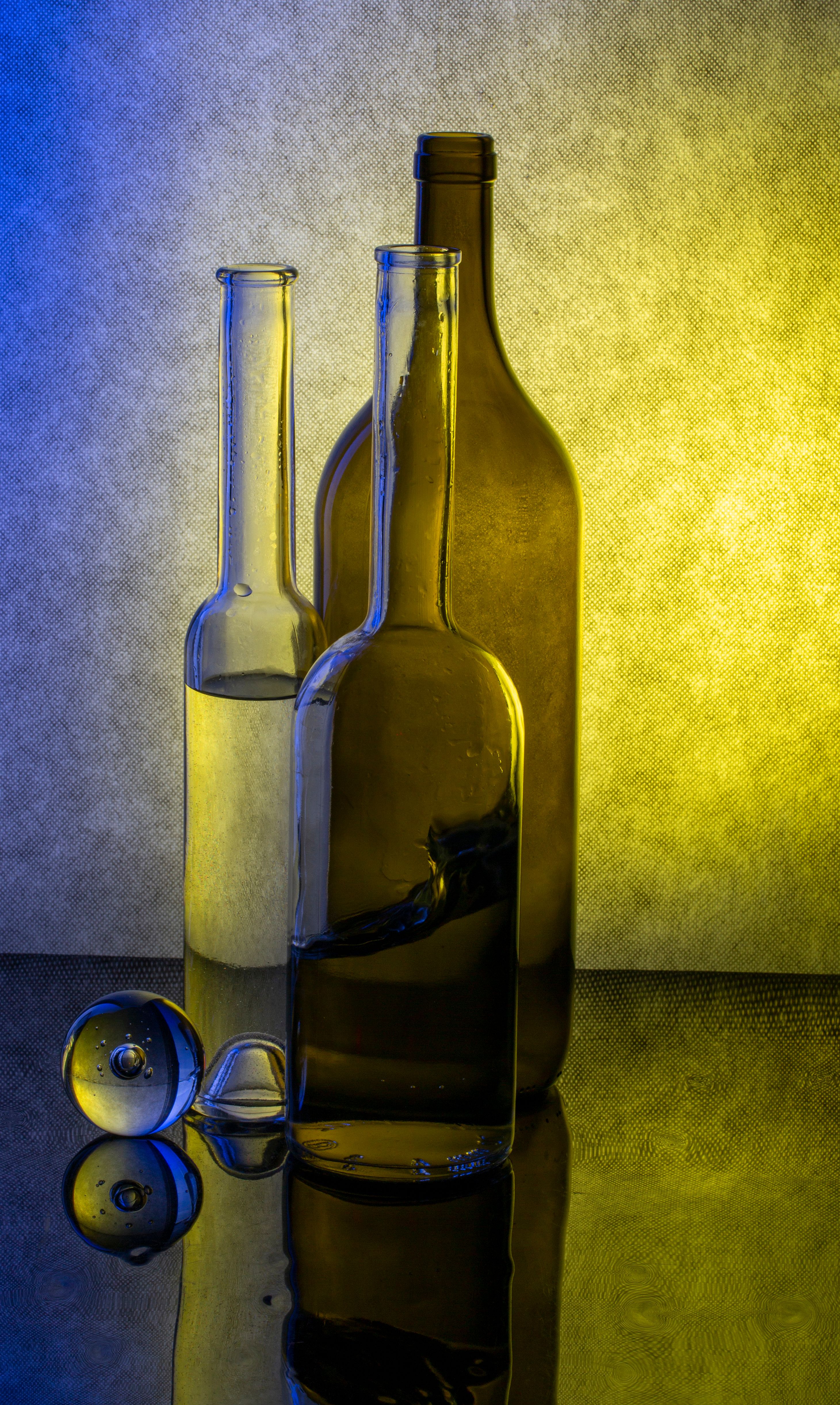 Fotomural Composición artística de botellas de vidrio con reflejos vívidos, capturada en un entorno de naturaleza muerta.