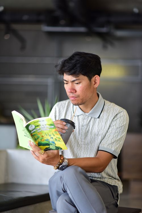 Free A man in a relaxed environment, sipping coffee and reading a book indoors. Stock Photo