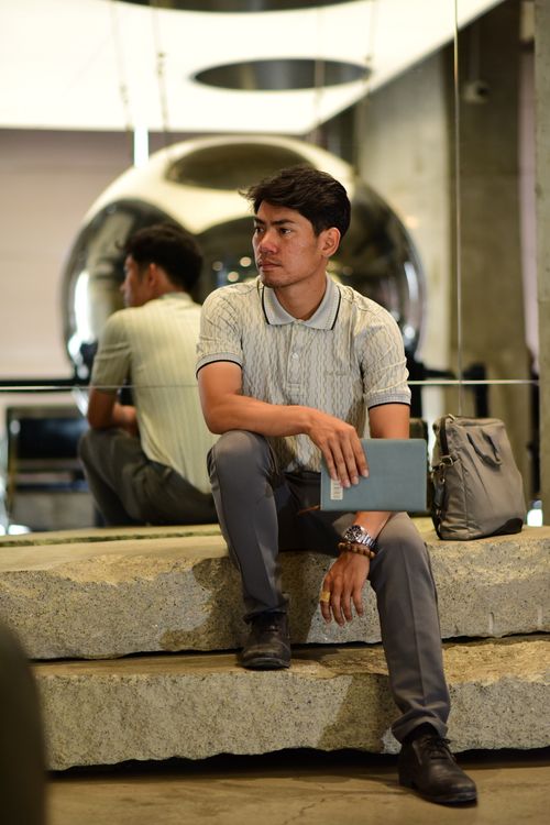 Free A man sits indoors holding a book, with reflections behind him. Stock Photo