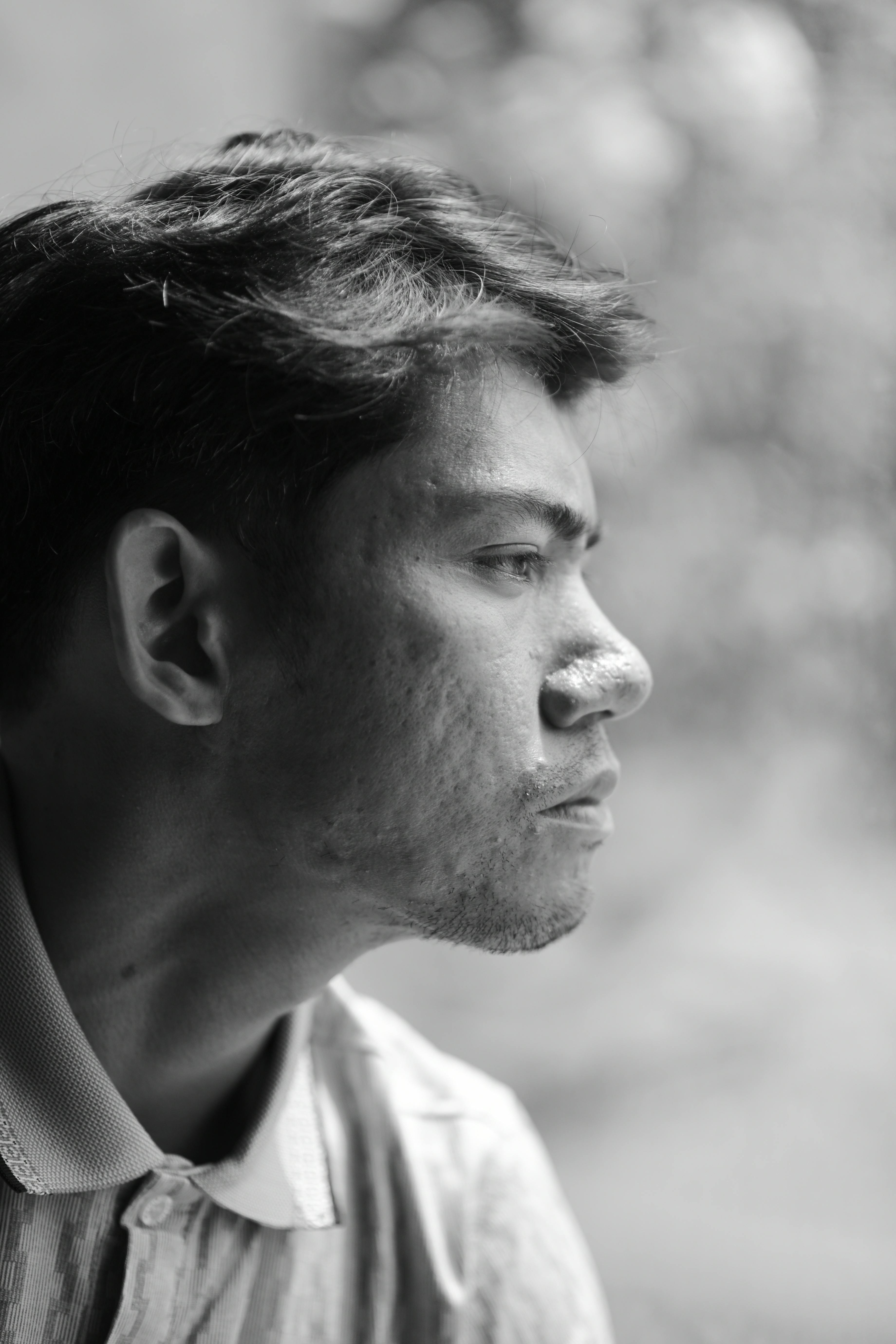 Black and white profile portrait of an adult man deep in thought, with soft natural lighting.