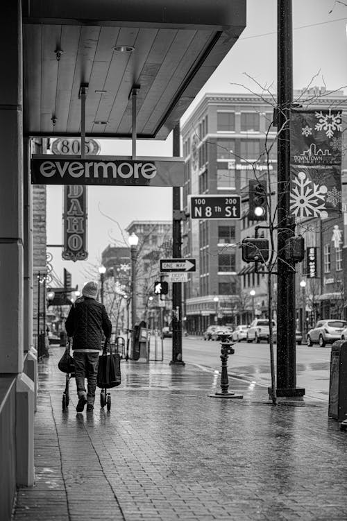 Grayscale Photo of Man Walking on Sidewalk