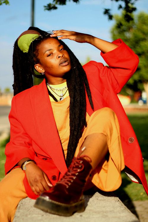 Free Stylish young woman in bright clothing poses outdoors on a warm sunny day. Stock Photo