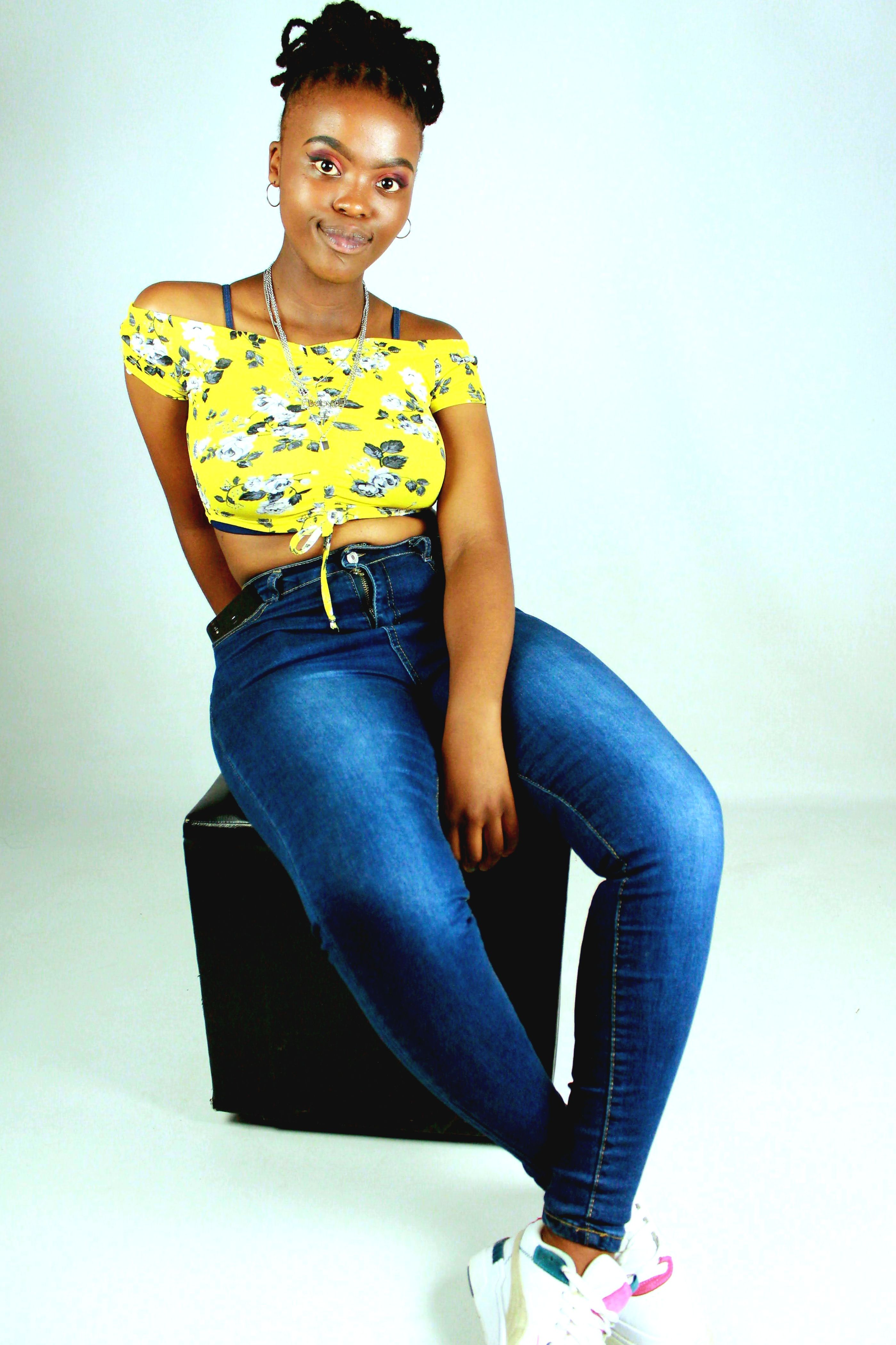 Fashionable young woman in casual attire sitting stylishly indoors.