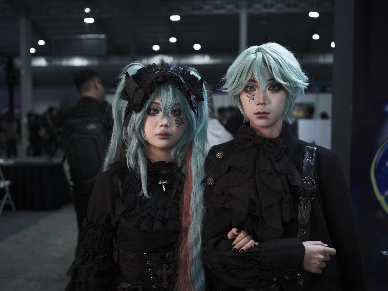 two adults in elaborate goth inspired cosplay costumes at an indoor co