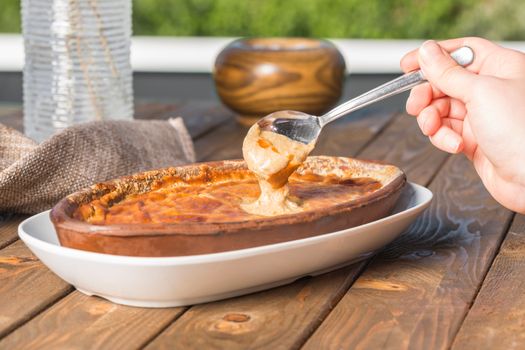 Delicious homemade Turkish Güveç in ceramic dish being served outdoors.