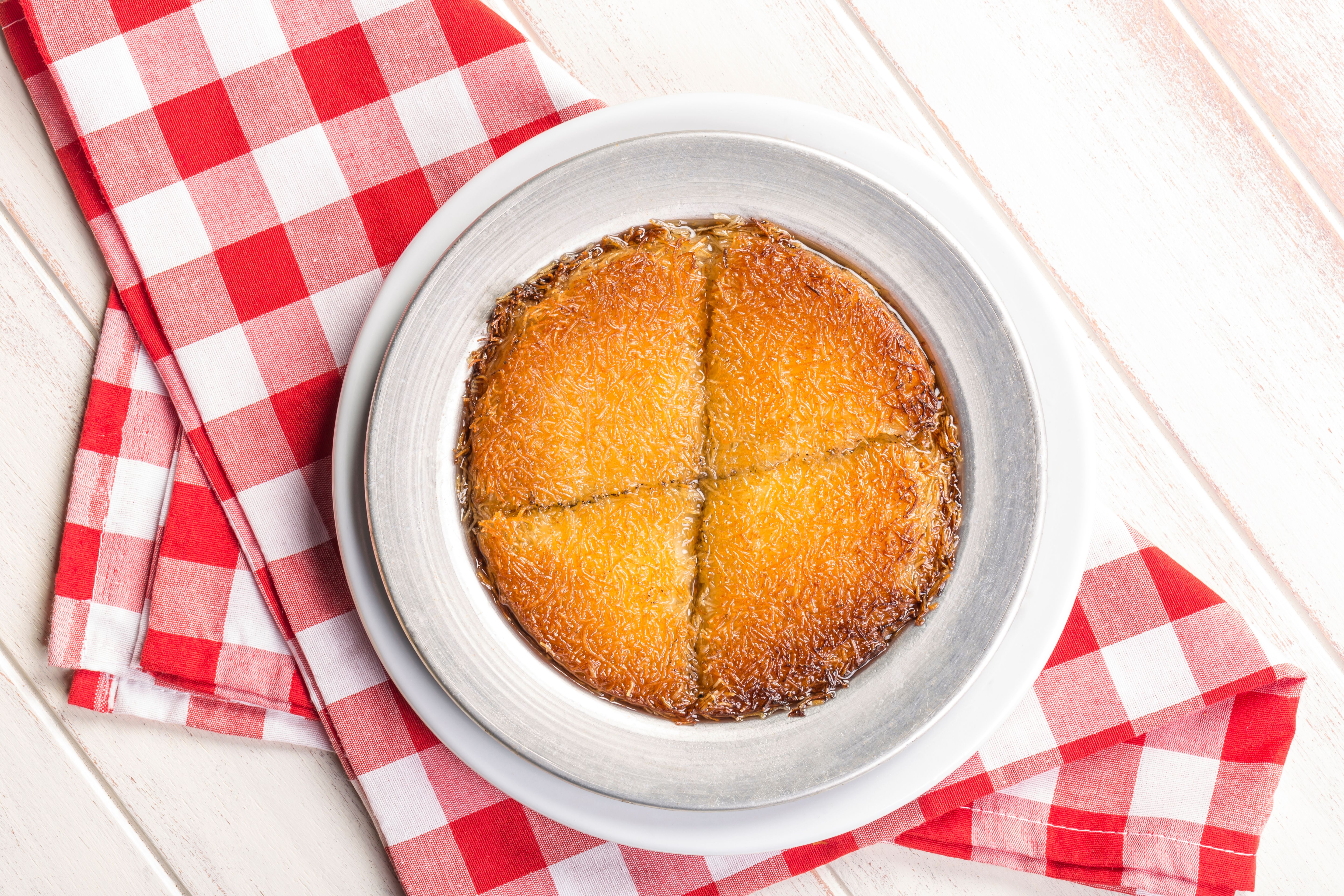 Close-up of traditional Turkish Künefe dessert on a checkered cloth in Bursa.
