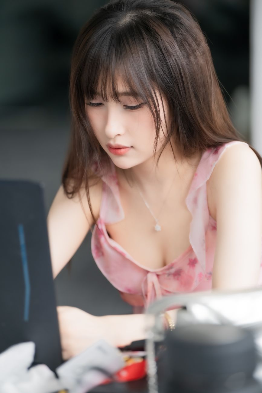 Young woman wearing a pink top working intently on a laptop indoors.
