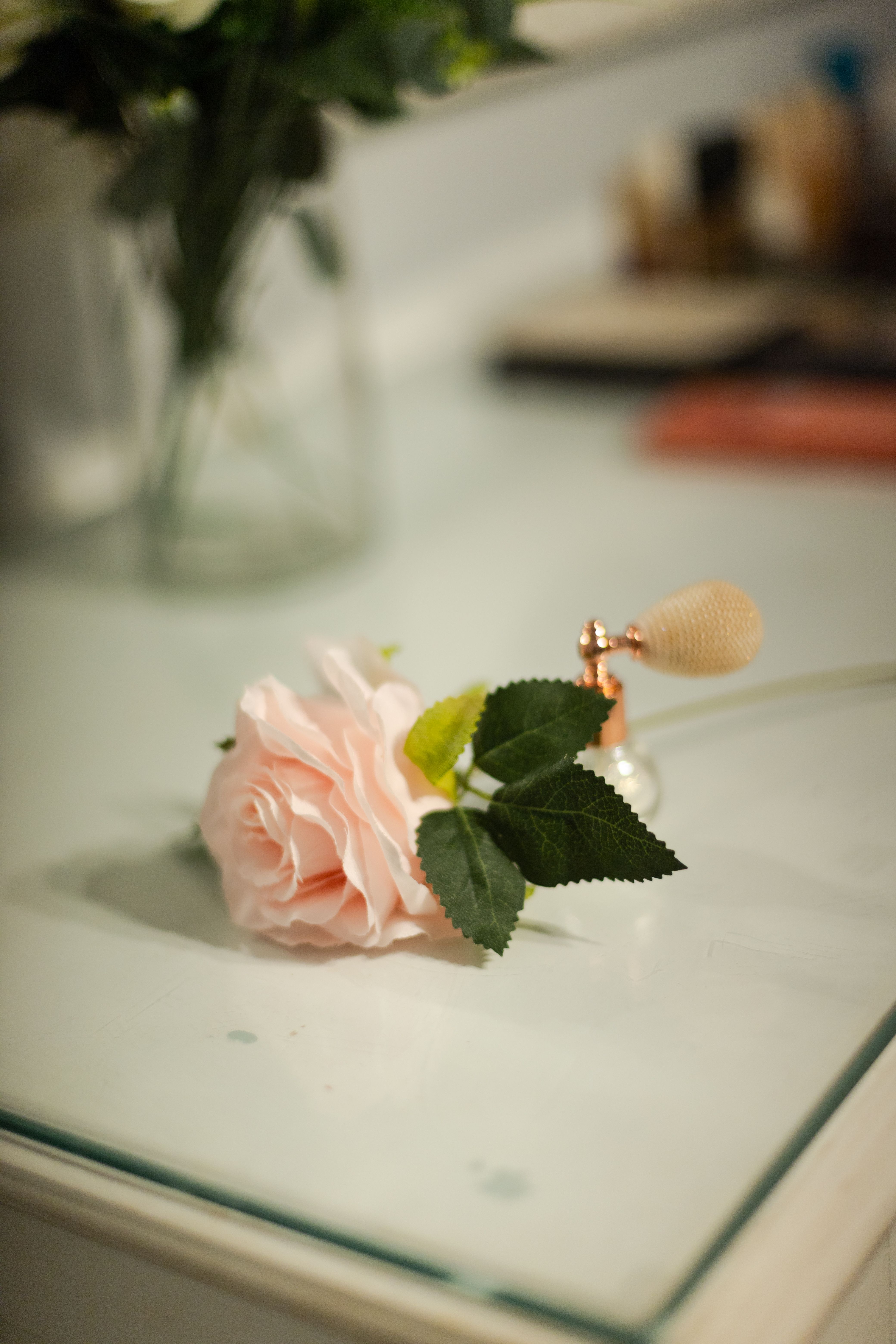 Delicate rose beside a vintage perfume bottle on a vanity