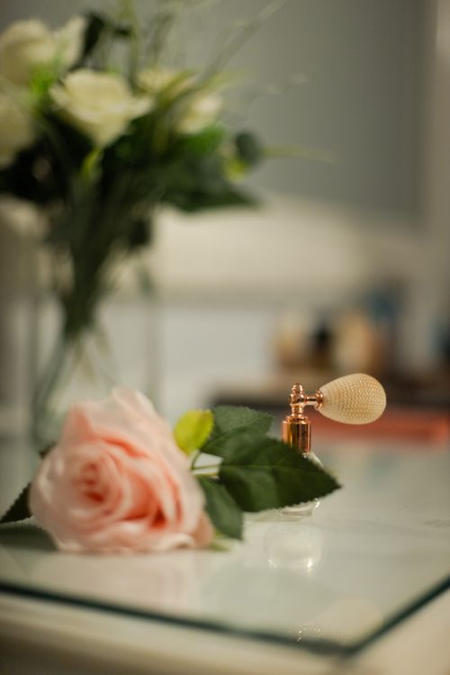 Free A perfume bottle and pink rose elegantly placed on a glass surface, creating a romantic atmosphere. Stock Photo