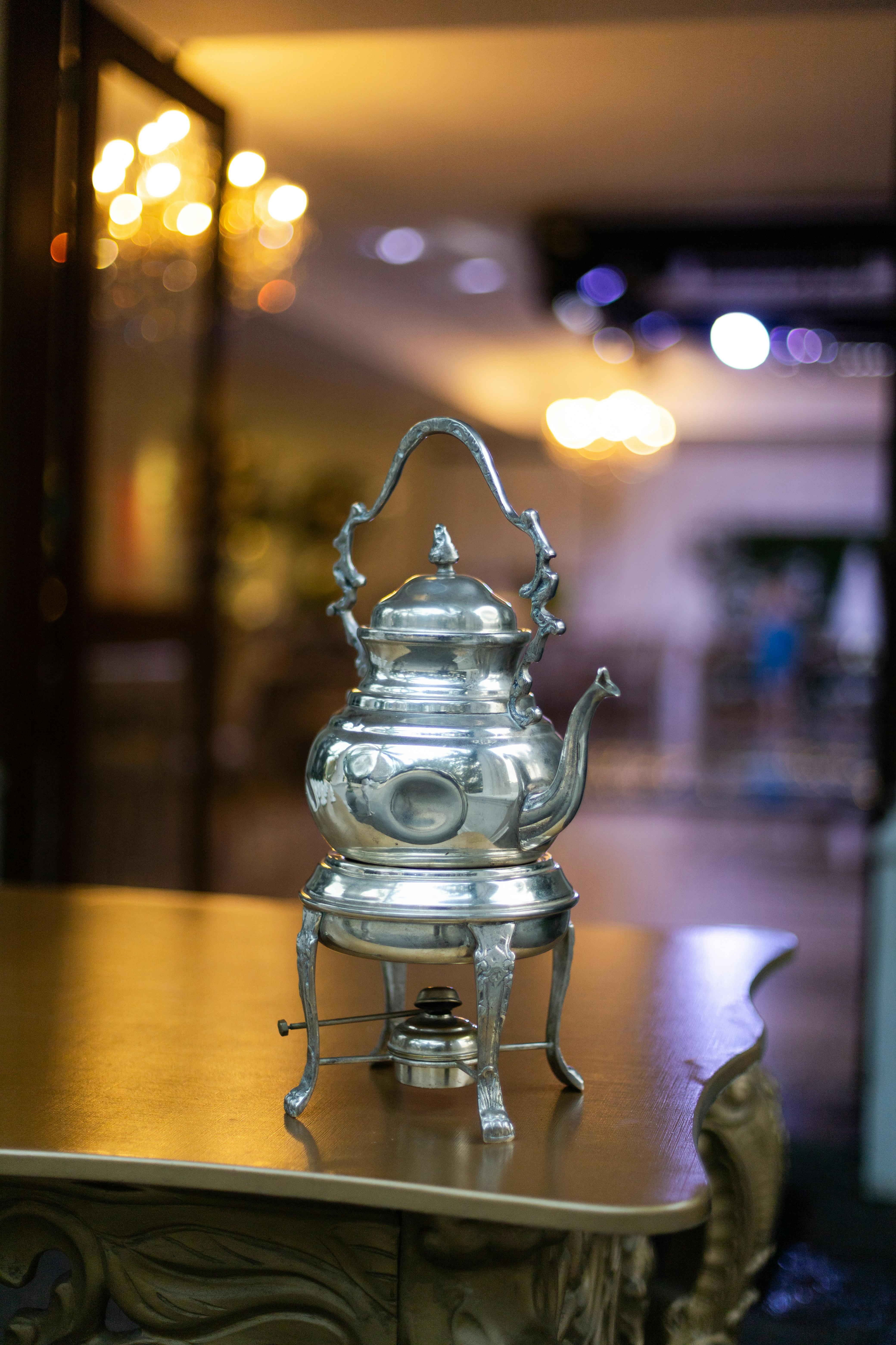 A beautiful silver teapot elegantly displayed on a vintage table with a blurred indoor background.