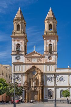 Facade of Parroquia de Santa Cruz in Cádiz, Spain, showcasing its Baroque architecture under a clear blue sky.