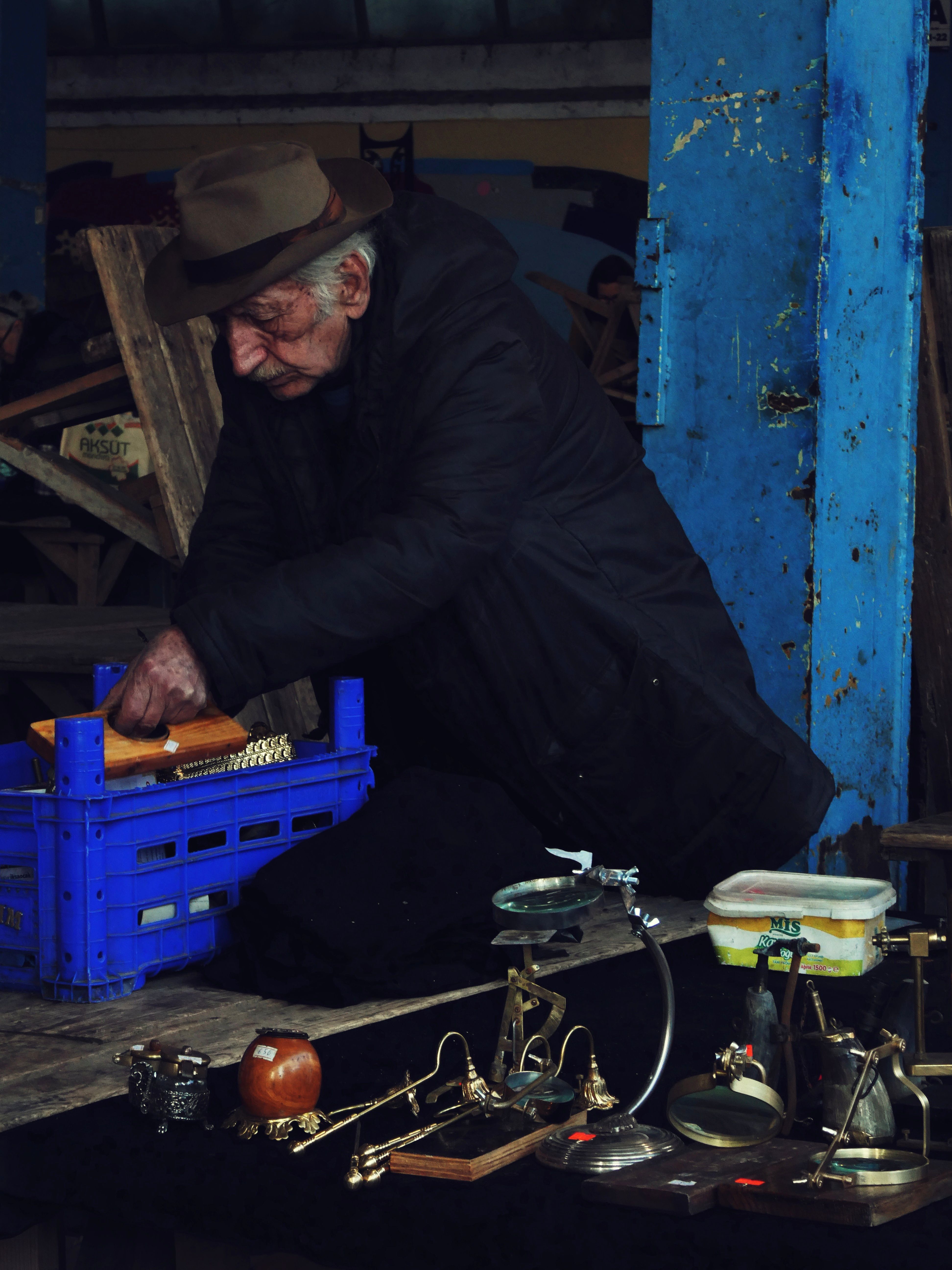 Senior man selling vintage items at an indoor market stall. Moody atmosphere.