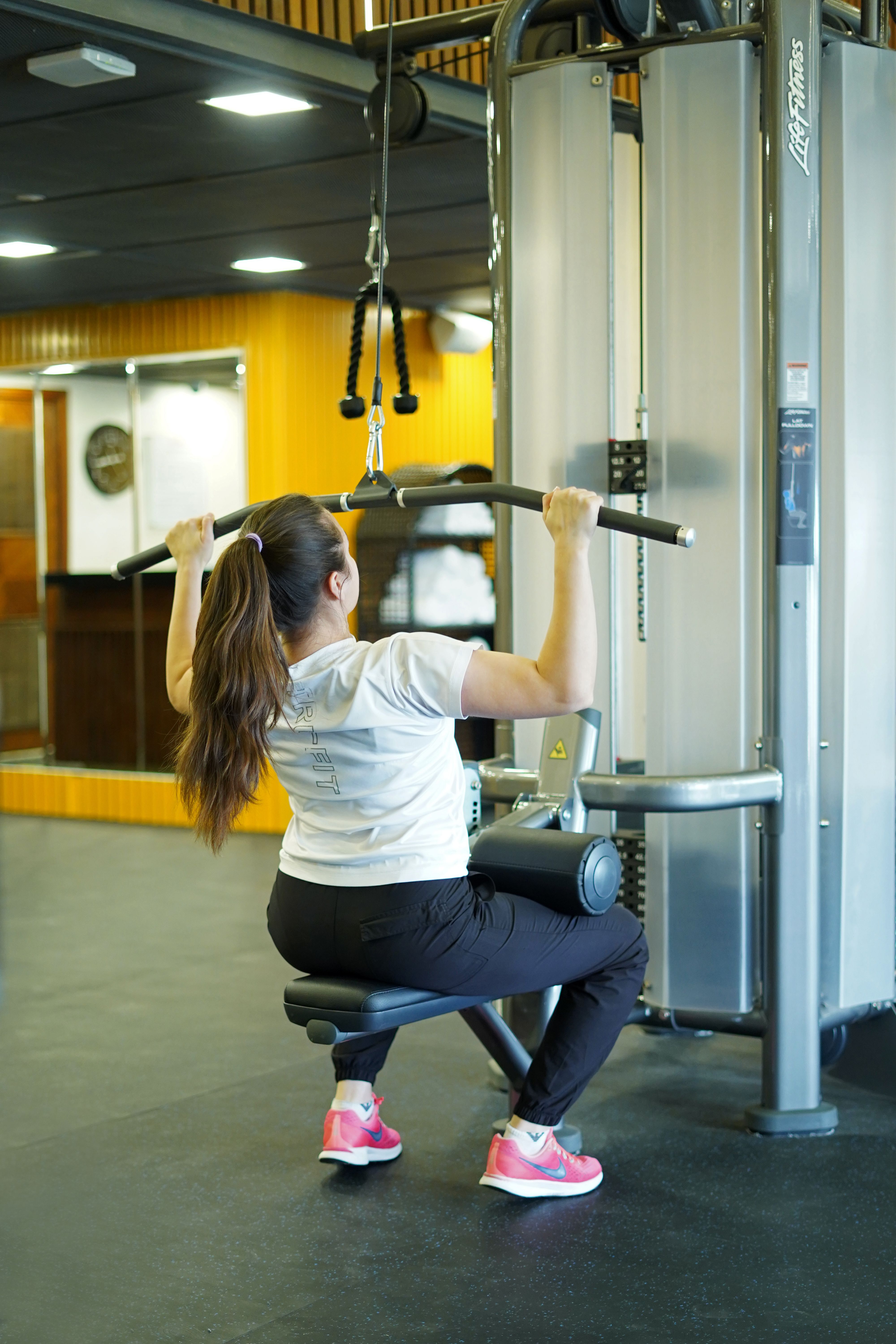 Femme utilisant une machine à tirage vertical en salle de sport