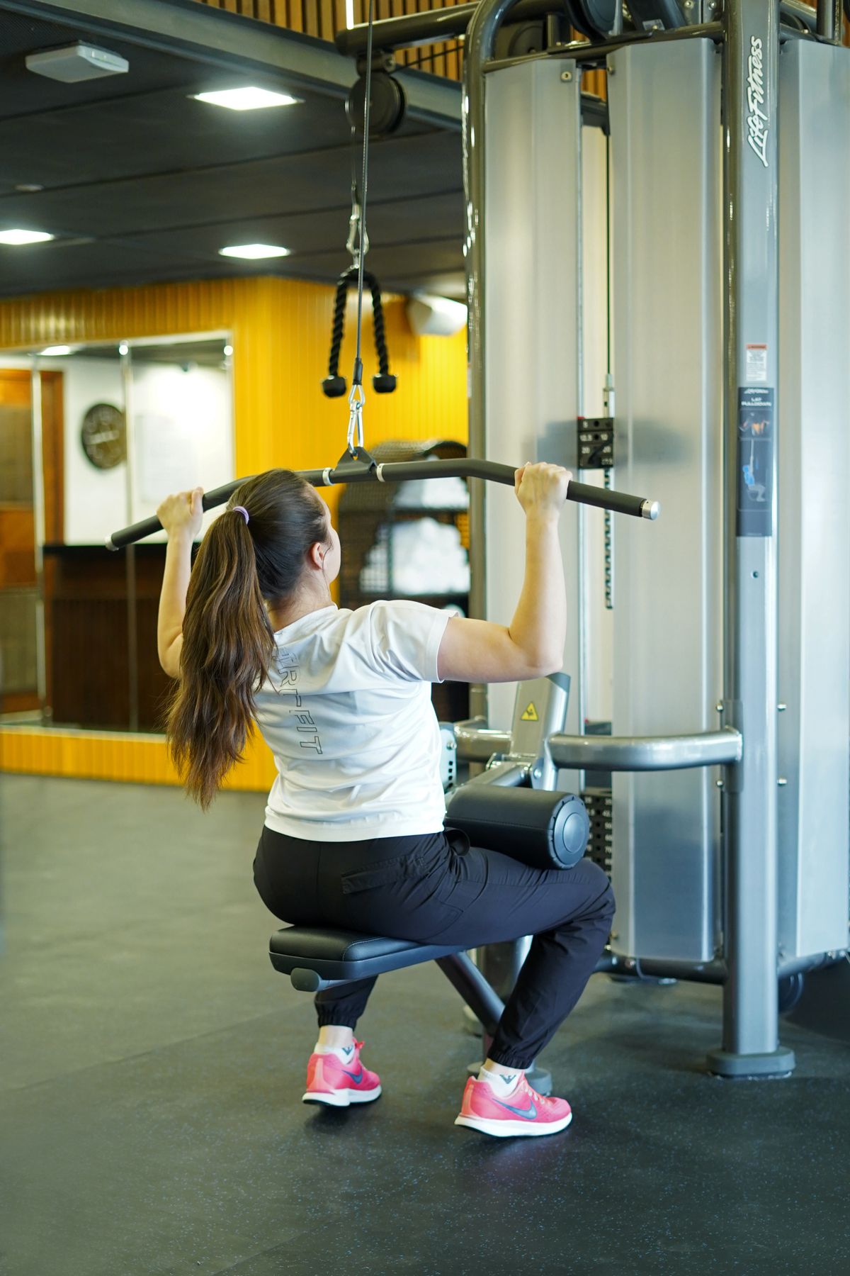 Woman using a lat pulldown station in a gym