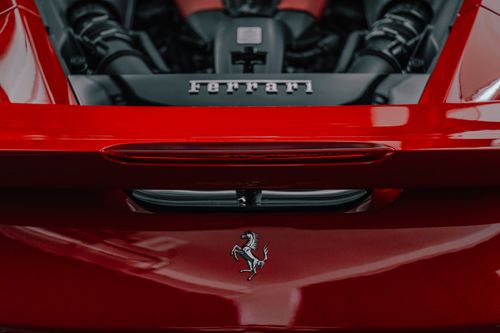 Free Detailed close-up of a red sports car exhibiting the emblem and engine bay, highlighting luxury and performance. Stock Photo