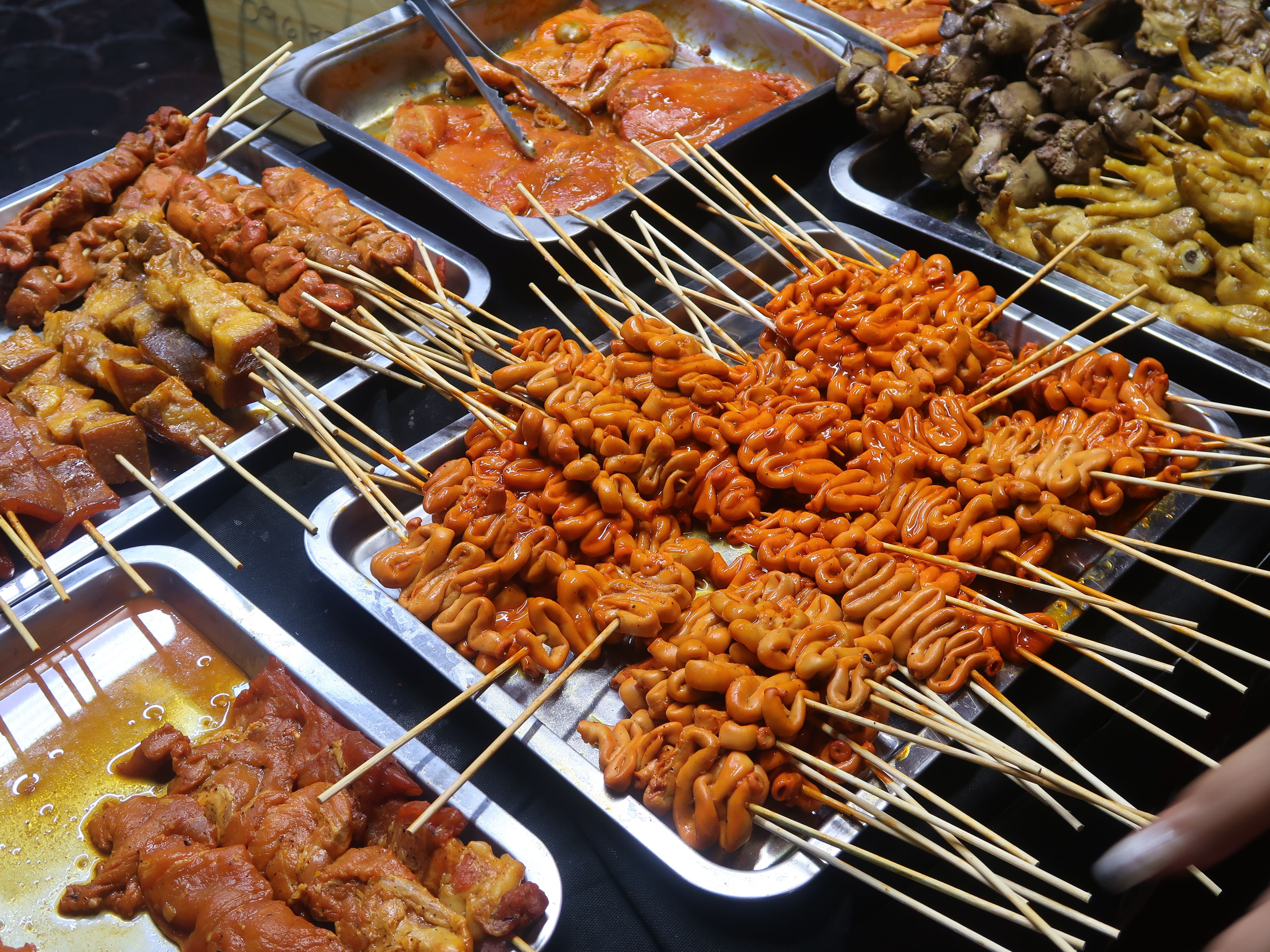 A vibrant display of Filipino street food skewers at an outdoor market in the Philippines.