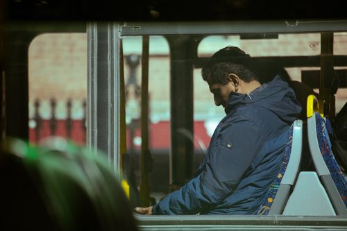 Free A person in a blue jacket seated inside a city bus during daytime commute. Stock Photo
