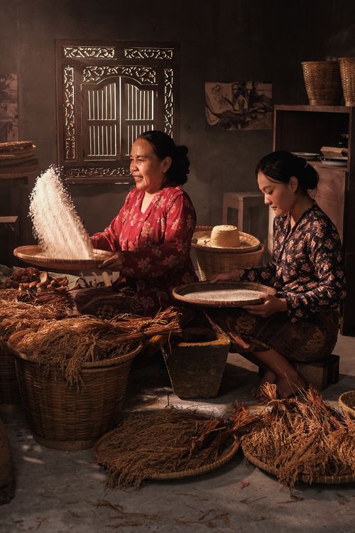 Free Two women in traditional attire preparing food with traditional tools in Jakarta, Indonesia. Stock Photo