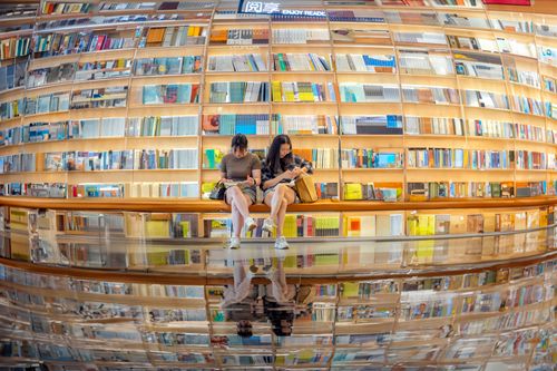 Free Two women reading in a modern library with a reflective glass floor in Shenzhen, China. Stock Photo