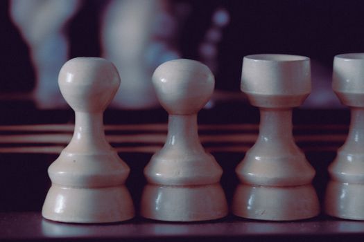 Elegant wooden chess pieces captured in soft, artistic lighting on a dark background.