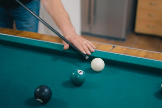A player taking aim at a pool table with billiard balls and cue stick.