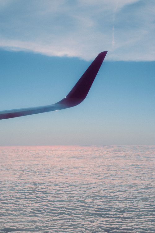 Free A stunning view of an airplane wing above clouds during sunrise, showcasing travel and adventure. Stock Photo