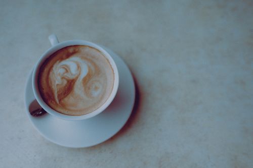 Free Top view of a latte with intricate art in a white cup on a saucer. Stock Photo