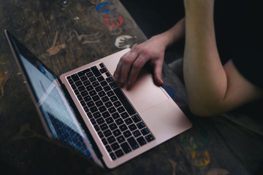 An adult uses a laptop on a rustic wooden desk, providing a cozy workspace vibe.