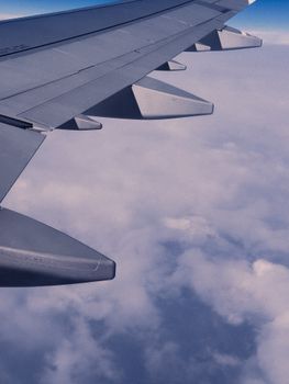 Airplane wing soaring above clouds, capturing serene view during daylight flight.