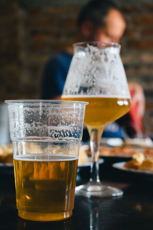 Free Two beer glasses on a table during a casual indoor social gathering. Stock Photo