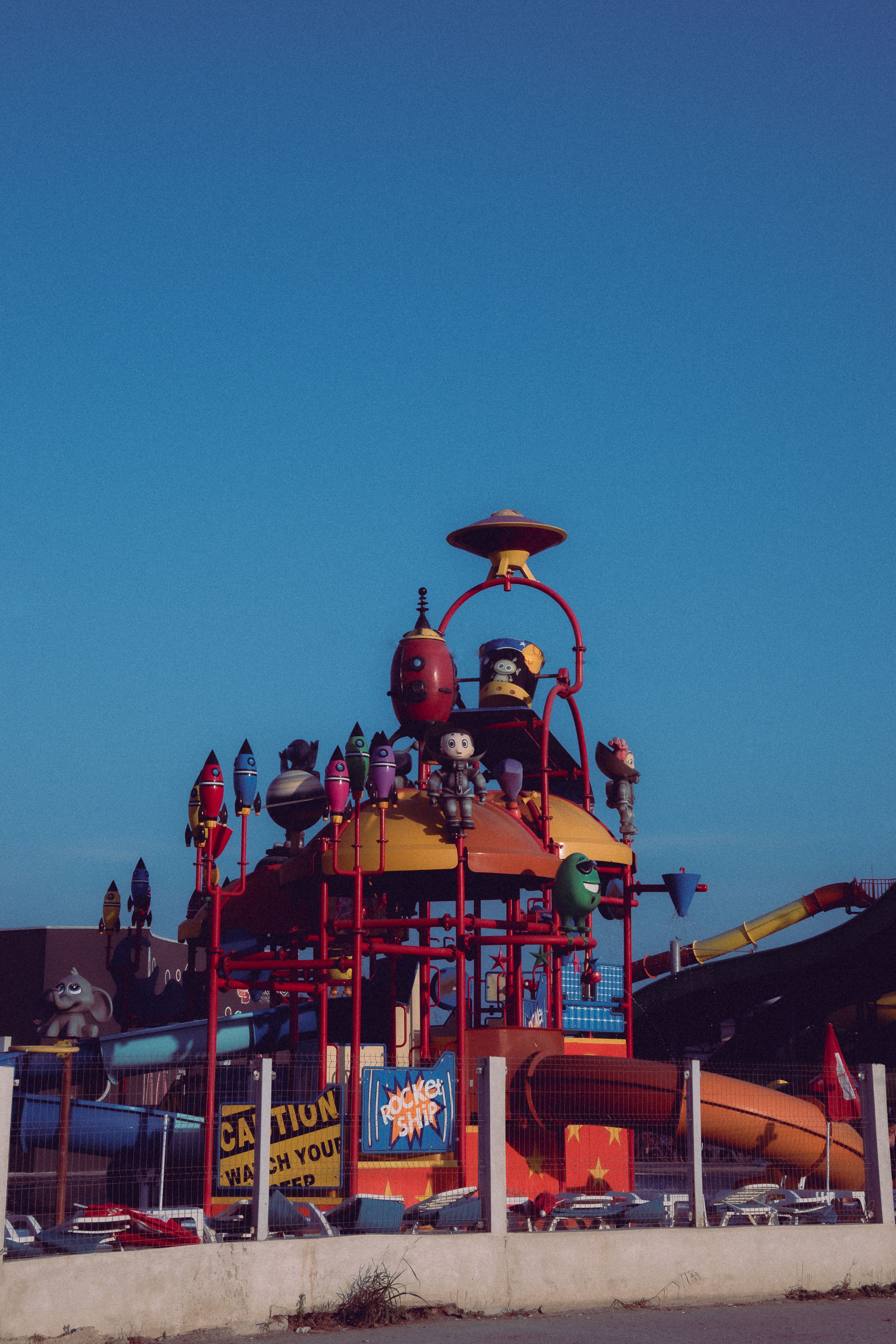 A colorful water park featuring a rocket ship theme under a clear blue sky.