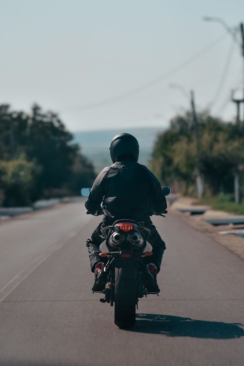 Free Lone motorcyclist riding a bike on an open road during the day. Stock Photo