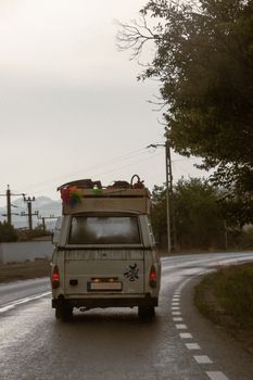 A nostalgic campervan travels down a winding road, loaded with adventure gear.