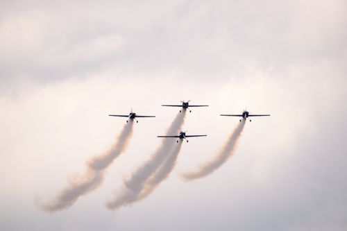 Free Four aerobatic planes flying in formation, trailing smoke against cloudy sky. Stock Photo