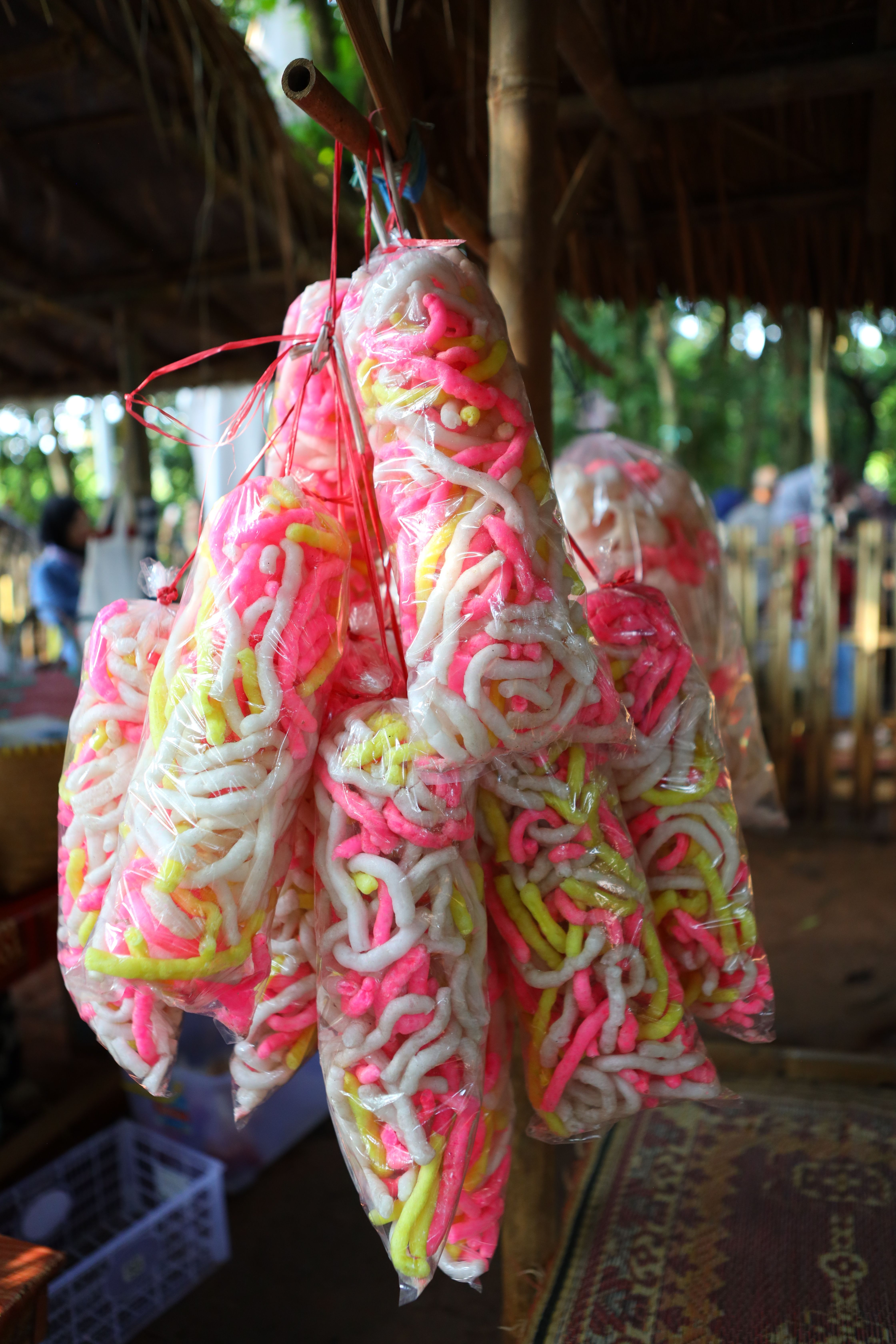 Colorful krupuk bags hanging in an Indonesian market, showcasing traditional snack.