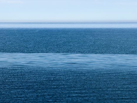 A tranquil view of the calm ocean under a clear blue sky, capturing serene and peaceful vibes.