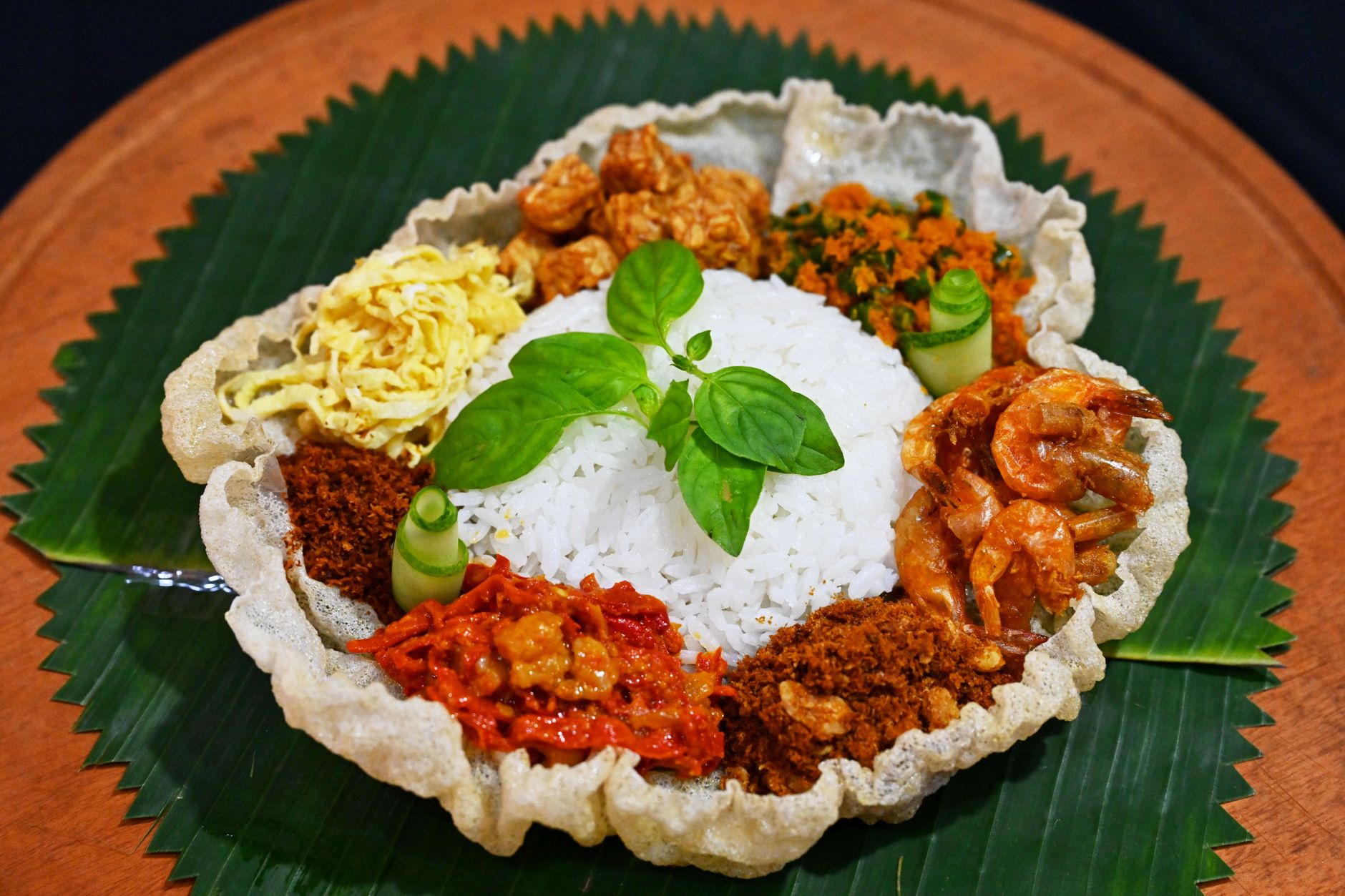 A vibrant display of Nasi Langgi, featuring rice, shrimp, and various side dishes on a banana leaf.