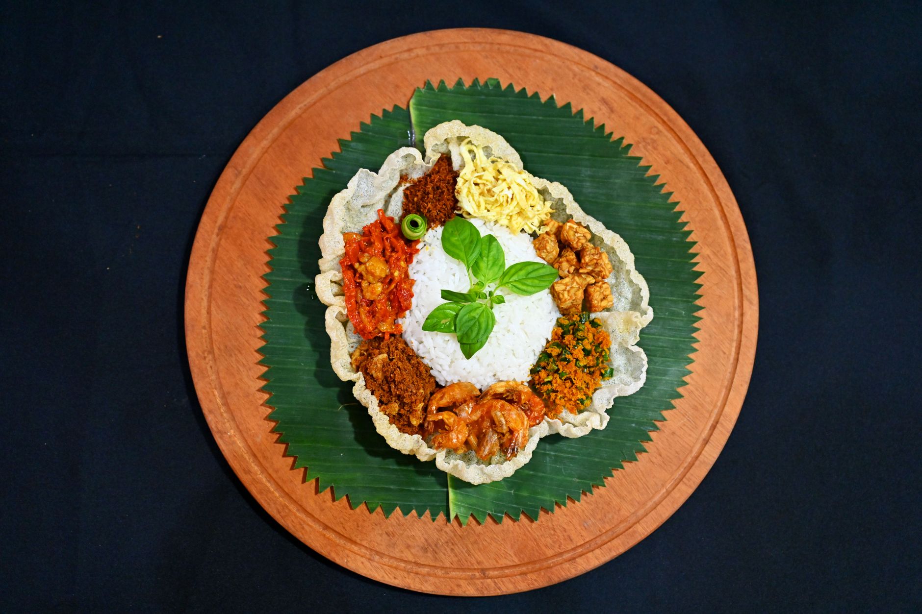 Traditional Nasi Langgi served with various side dishes on a banana leaf in Bandung, Indonesia.